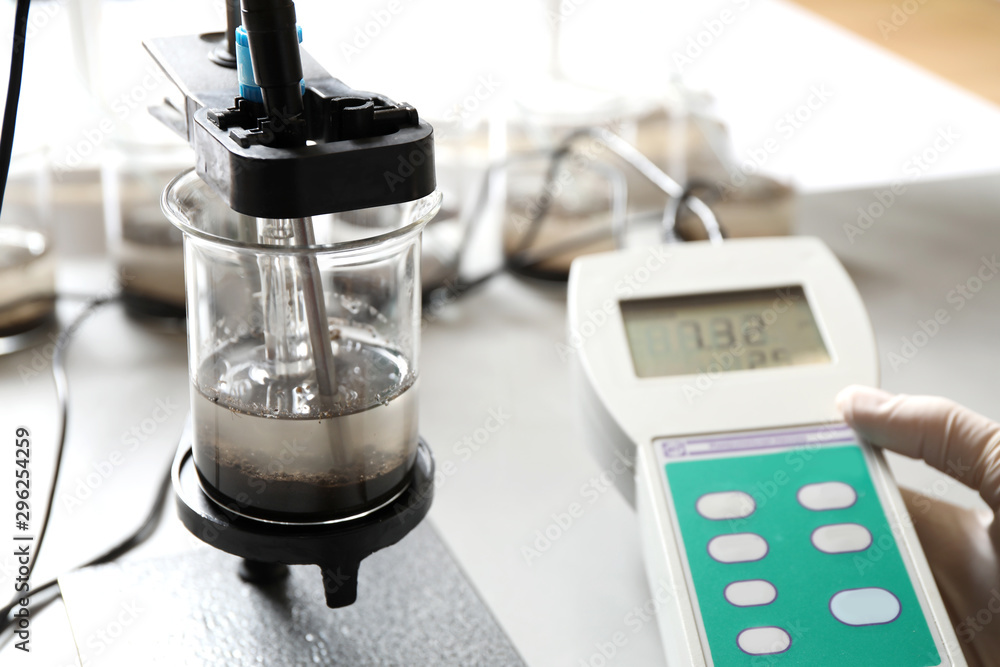 Scientist measuring acidity and pH of soil at table, closeup ...