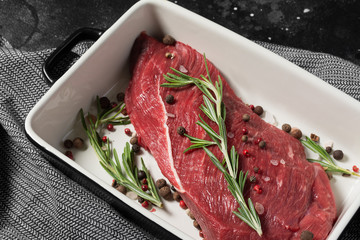 Raw beef in ceramic baking dish on black kitchen table	