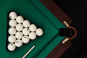 Billiard balls in triangle and cue on table, flat lay