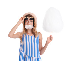 Wall Mural - Happy young woman eating cotton candy on white background