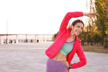 Sticker - Young woman with wireless headphones listening to music while exercising outdoors. Space for text