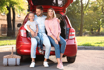 Canvas Print - Happy family sitting in car's trunk outdoors