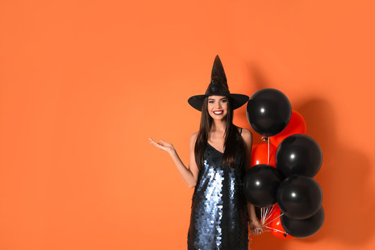 Beautiful woman wearing witch costume with balloons for Halloween party on yellow background, space for text