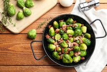 Flat Lay Composition Of Tasty Roasted Brussels Sprouts With Bacon On Wooden Table