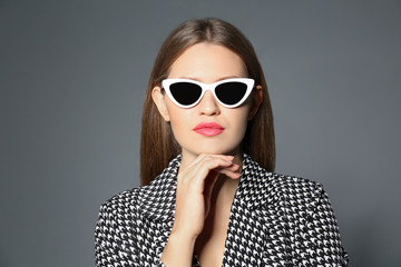 Wall Mural - Young woman wearing stylish sunglasses on grey background