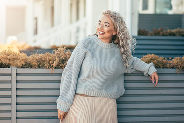 Plus size model with blond curly hair in knitted sweater outdoor