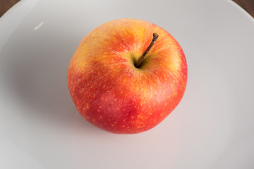 red and yellow apple on a white plate on a white background