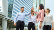© FotoArtist - Low Angle View Of Friends High-Fiving Against building in city