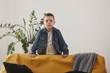 © standret - Child stands in the living room near the yellow sofa and green plant. White background