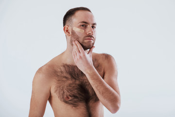 Wall Mural - Here's what happening when you shave your beard not carefully. Man with bare chest stands against white background in the studio