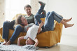 © standret - Having leisure. Happy family have fun on the yellow sofa in the living room of their new house