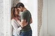 © standret - Awesome mood. Lovely couple kissing and enjoying each other near the window of their new home