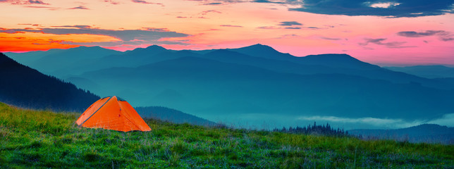 Wall Mural - orange tent in mountains at sunset