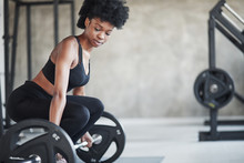 Lifting Exercises. African American Woman With Curly Hair And In Sportive Clothes Have Fitness Day In The Gym