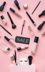 Wall Mural - Cosmetic and perfume female products accessories promotion offer with sale tag beauty makeup fashion items objects set with shopping bags on pink table background, flat lay, vertical above top view