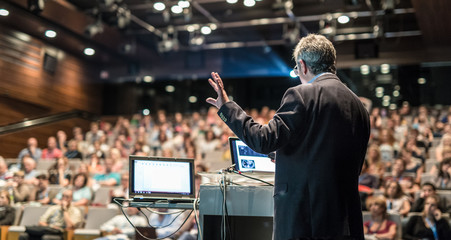 speaker giving a talk on corporate business conference. unrecognizable people in audience at confere