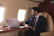 © LIGHTFIELD STUDIOS - pensive businessman holding cup of coffee in plane with laptop during business trip