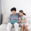 © nuiiko - Asian senior woman and girl using tablet at home, lifestyle concept.