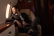 © LIGHTFIELD STUDIOS - handsome man holding glass of champagne in aircraft