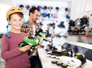 Wall Mural - Cheerful boy customer examining roller-skates