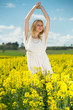 © JackF - Young woman in yellow oilseed rape  field stretch oneself outdoor
