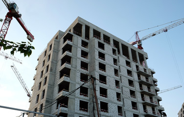 Urban construction. Jib cranes around modern city building in construction process