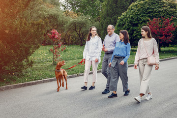 Family in a summer park. People walking with a dog. Parents with a two daughters