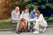 © hetmanstock2 - Family in a summer park. People sitting with a dog. Parents with a two daughters