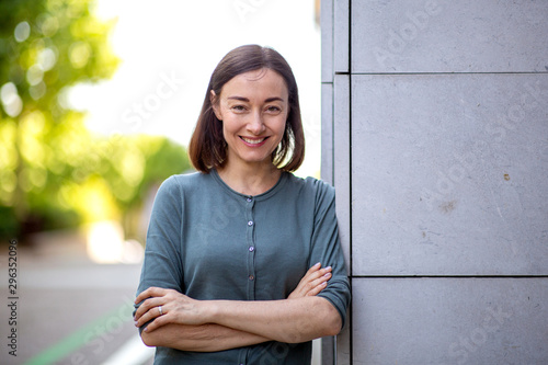 Cuadros en Lienzo beautiful middle aged woman leaning against wall and smiling with arms crossed