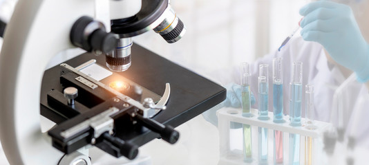 Wall Mural - close-up shot of microscope with metal lens at laboratory with blurred background of scientist use d