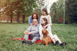 © hetmanstock2 - Family in a summer park. People sitting with a dog. Parents with a two daughters