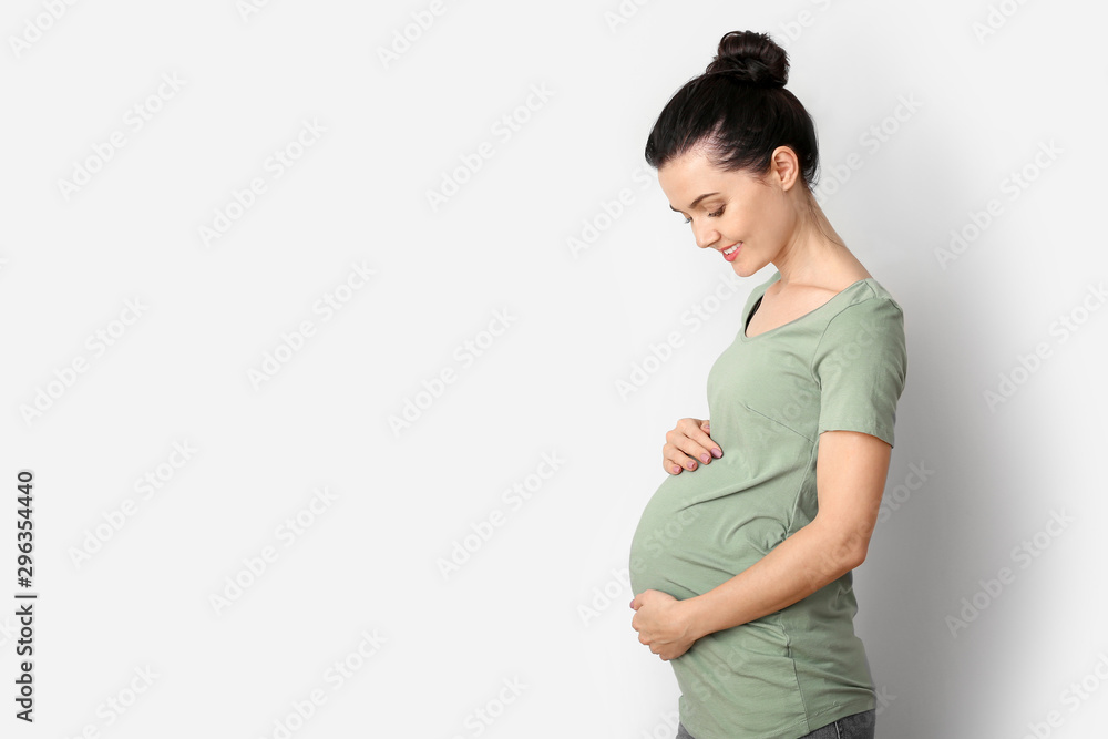 Beautiful young pregnant woman on light background