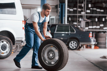 Wall Mural - Going forward. Employee in the blue colored uniform works in the automobile salon