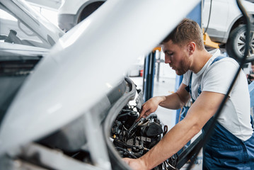 Wall Mural - Bus is repairing. Employee in the blue colored uniform works in the automobile salon