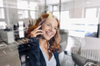 © Kniel Synnatzschke/Westend61 - Happy redheaded businesswoman on the phone in office