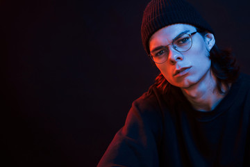 Elegant guy. Studio shot in dark studio with neon light. Portrait of serious man