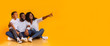 © Prostock-studio - Happy family of three sitting on floor and pointing aside