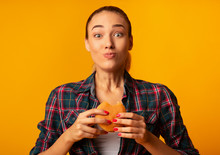 Girl Eating Burger Having Cheat Meal Standing On Yellow Background