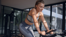 Young Beautiful Girl On An Exercise Bike In A Gym. Cycling