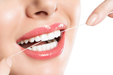 Wall Mural - Young beautiful woman is engaged in cleaning teeth. Beautiful smile healthy white teeth. A girl holds a dental floss. The concept of oral hygiene. Promotional image for a dental clinic.