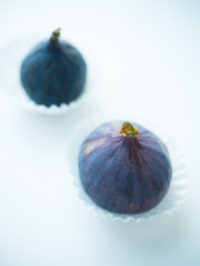 Two ripe sweet figs in paper and white table. Selective focus