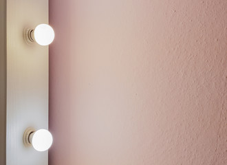 Modern new flat pink wall with two light bulbs from a large floor mirror for makeup and full-length shopping. Abstract modern trendy texture background. Copy space for your text.