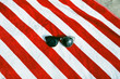 © Jonathan Schultz - Pair of sunglasses on red and white striped beach towel