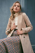 Beautiful casual blond girl in trench coat confidently looking in camera outdoor