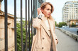 © Anton - Beautiful casual blond girl in stylish trench coat thoughtfully looking aside on bridge