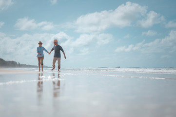 Wall Mural - Senior couples walking hand in hand on the beach at sunny day, plan life insurance with the concept of happy retirement.