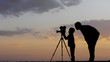 © MEDIAIMAG - Father and son silhouettes looking at photo camera, child carry on parent job
