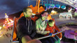 © MEDIAIMAG - Parents and child having fun in amusement park, night entertainment