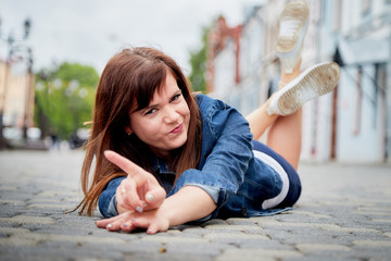 Brunette funny pretty girl on pavement in Central part of ancient city. Walk in downtown. Portrait of girl on street