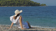 © MEDIAIMAG - Single woman with hat sit on beach sand and admire blue waiving sea, serenity